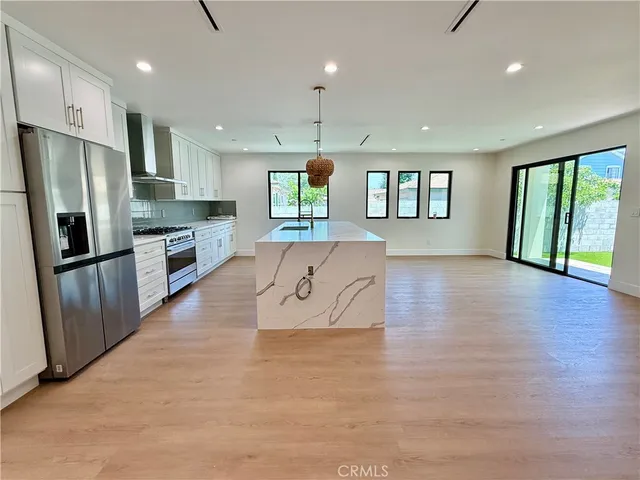 a large kitchen with granite countertop a large counter top stainless steel appliances a window and a refrigerator