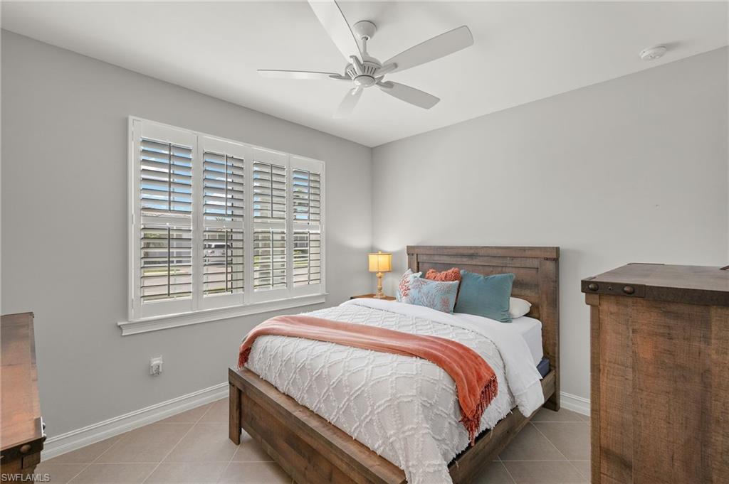14671 Topsail Drive Naples, FL 34114 - Photo 17 of 36 a bed sitting in a bedroom next to a window and a chandelier
