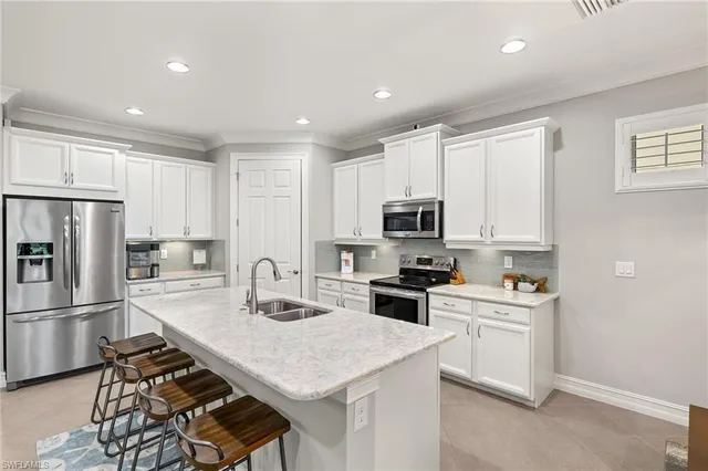 a kitchen with a sink a stove a refrigerator cabinets and a dining table