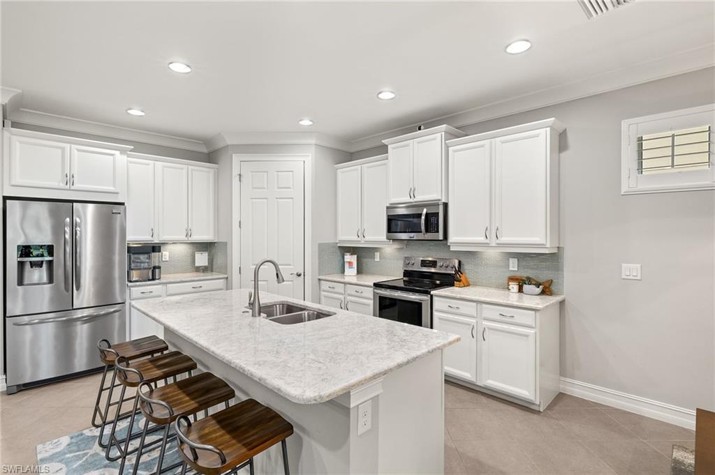 14671 Topsail Drive Naples, FL 34114 - Photo 7 of 36 a kitchen with a sink a stove a refrigerator cabinets and a dining table