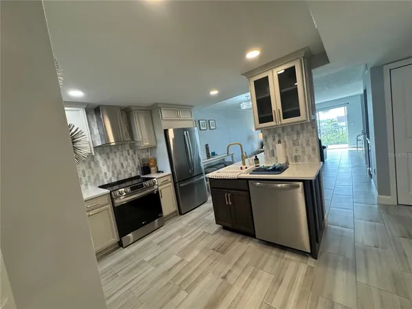 a large kitchen with stainless steel appliances granite countertop a stove a sink dishwasher and a refrigerator with wooden floor