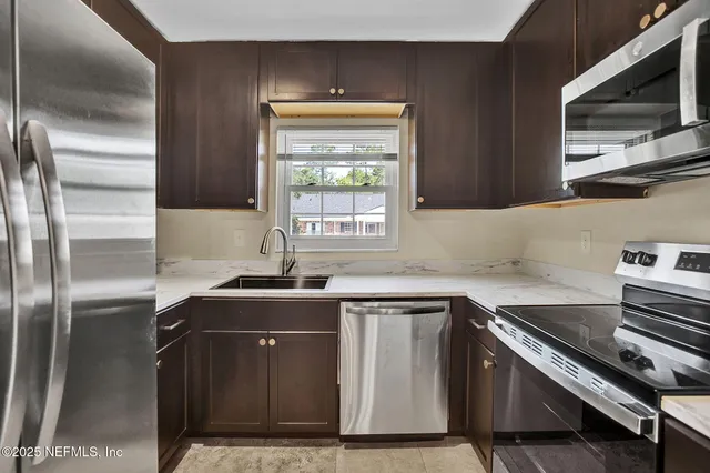 a kitchen with granite countertop a sink stainless steel appliances and cabinets