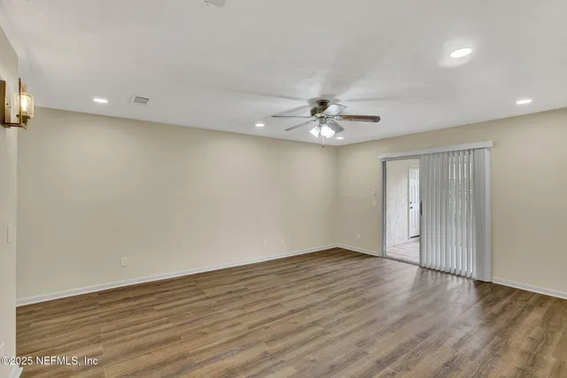 a view of an empty room with wooden floor and chandelier