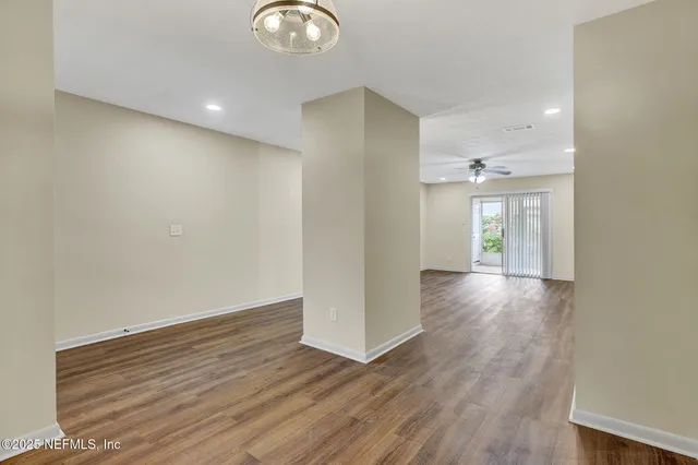 an empty room with wooden floor cabinet and windows