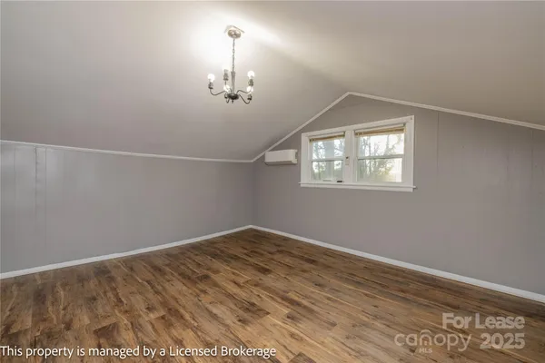 a view of an empty room with wooden floor and a chandelier