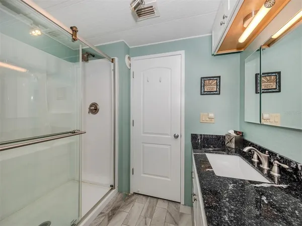 a bathroom with a granite countertop shower sink and mirror