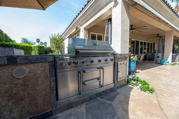 a view of a backyard with table and chairs potted plants and large tree