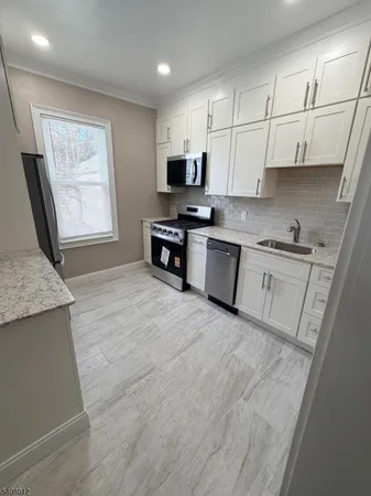 a large kitchen with stainless steel appliances granite countertop a stove a sink dishwasher and a refrigerator with wooden floor