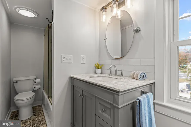 a bathroom with a granite countertop sink toilet and a mirror