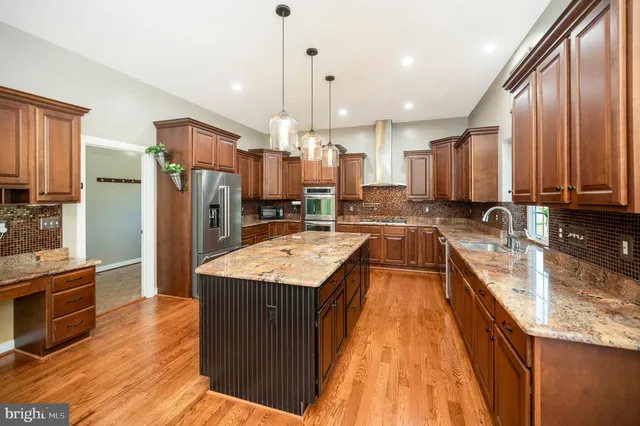 a kitchen with stainless steel appliances granite countertop a refrigerator a stove and a sink