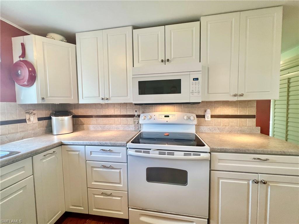 273 Cape Sable Drive Naples, FL 34104 - Photo 8 of 49 a kitchen with white cabinets and appliances
