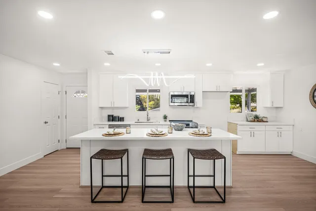 a kitchen with a dining table chairs stove microwave and cabinets