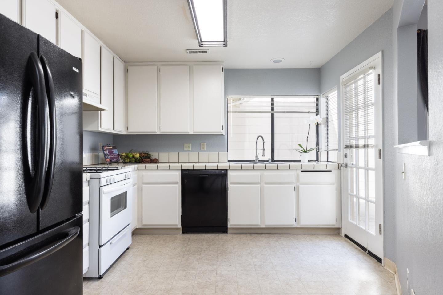 1061 Olympic Lane Seaside, CA 93955 - Photo 10 of 24 a kitchen with white cabinets and white appliances