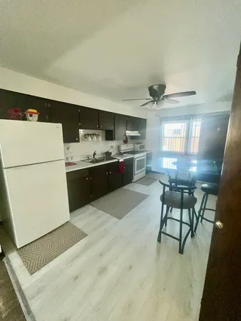 a kitchen with kitchen island a stove a refrigerator and a dining table with wooden floor
