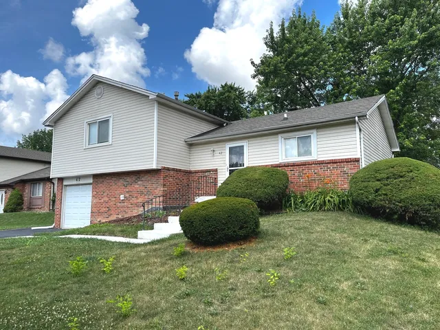 a view of a house with a yard and a large tree