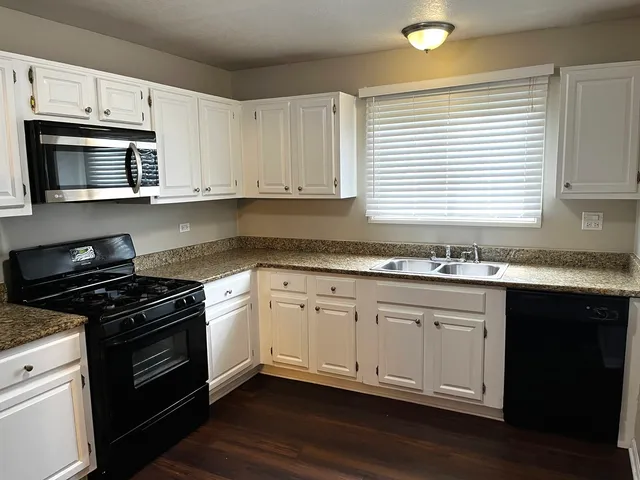 a kitchen with granite countertop cabinets stainless steel appliances and wooden floor