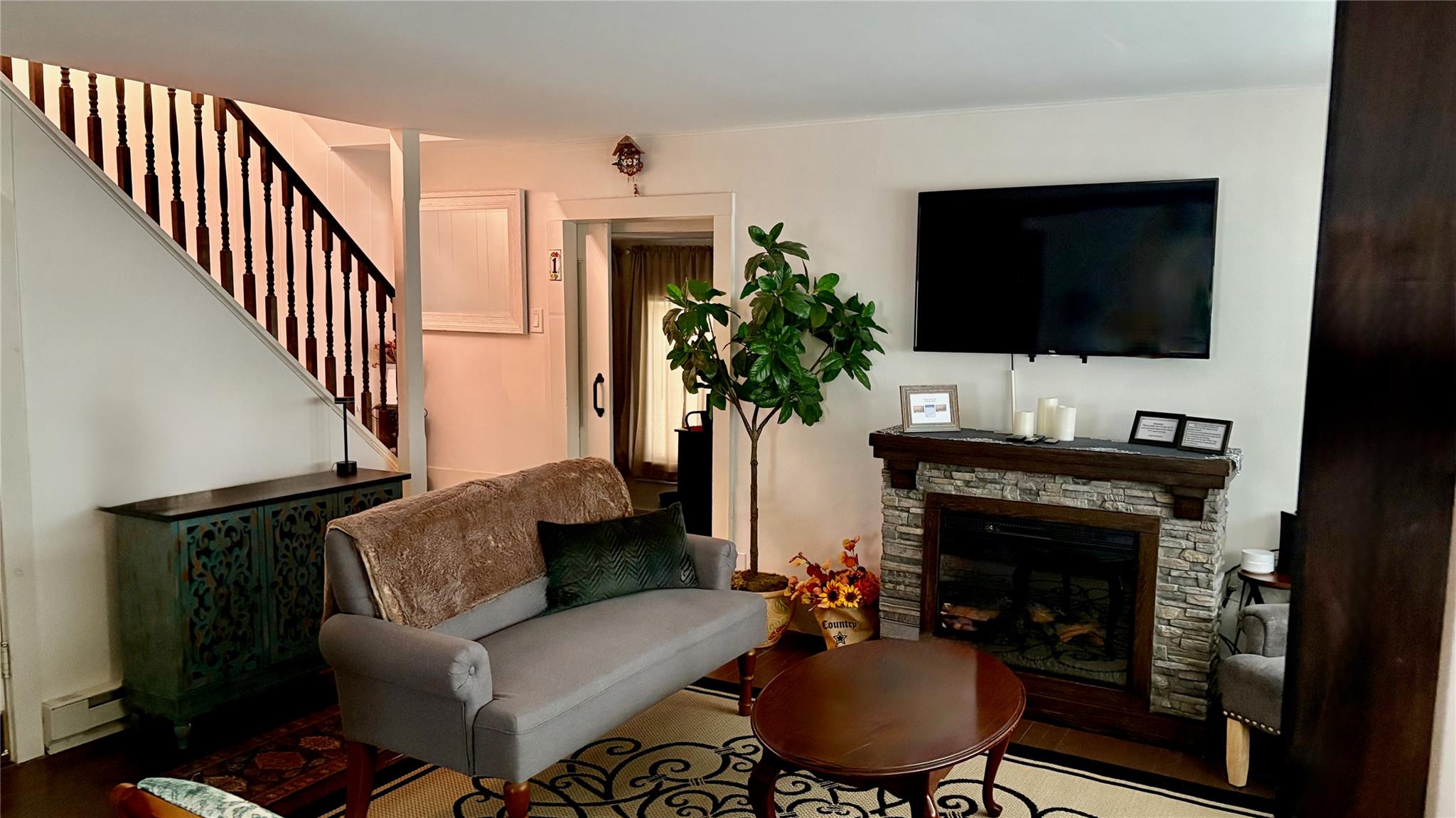21 Mitchell Avenue Callicoon, NY 12723 - Photo 16 of 33 Living area featuring a baseboard heating unit, stairs, a fireplace, and wood finished floors
