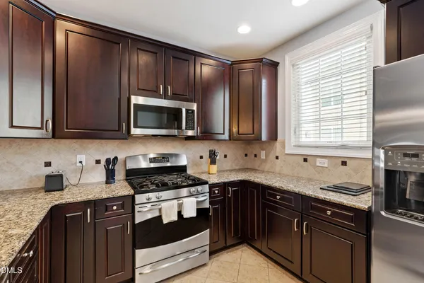 a kitchen with stainless steel appliances granite countertop a sink a stove and a wooden cabinets
