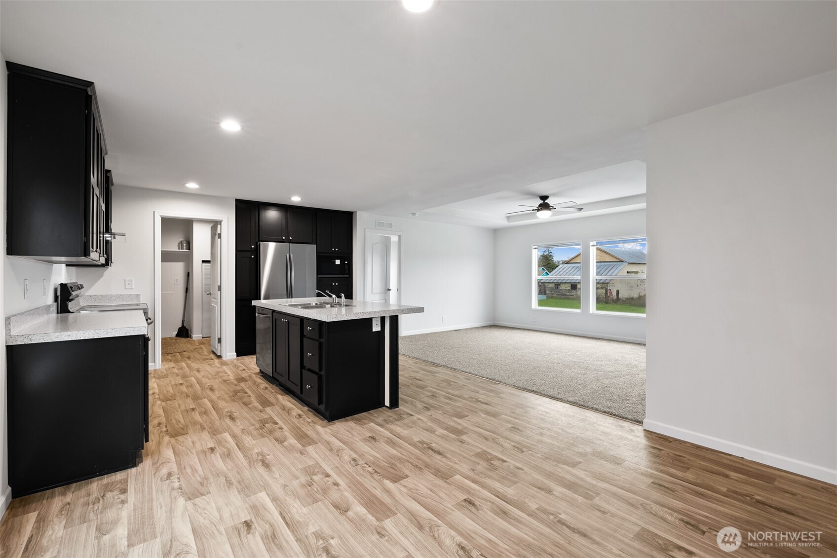 591 North Lees Creek Road Port Angeles, WA 98362 - Photo 13 of 39 a living room with stainless steel appliances kitchen island granite countertop a refrigerator a sink dishwasher and a black countertops with wooden floor