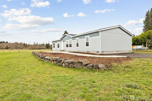 a white house with a big yard and plants
