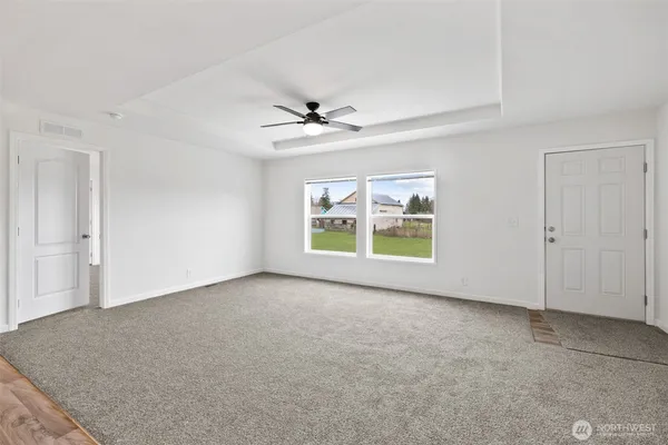 an empty room with windows and ceiling fan