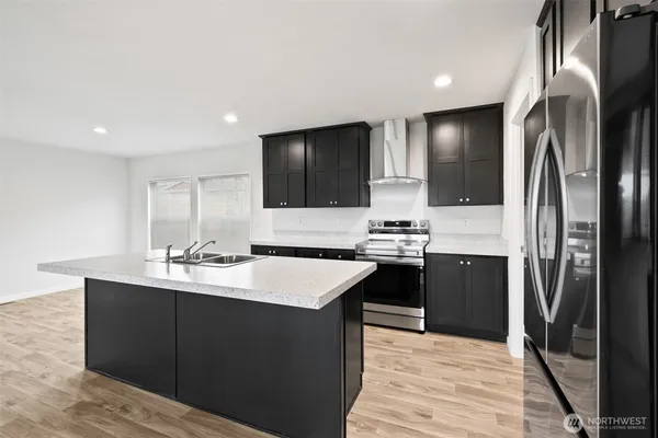 a kitchen with stainless steel appliances kitchen island granite countertop a refrigerator stove and sink