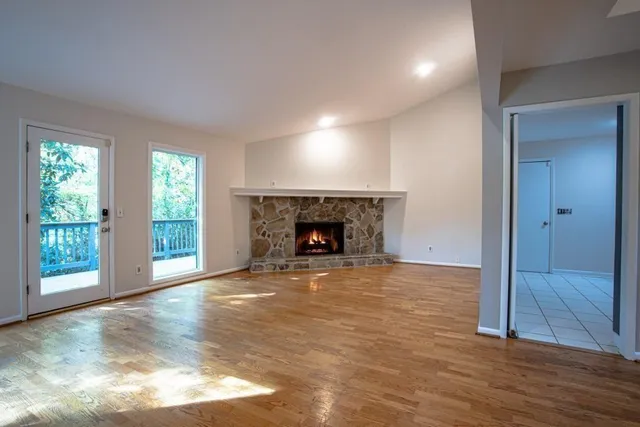 an empty room with wooden floor fireplace and windows