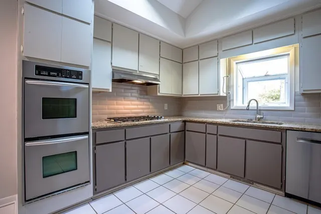 a kitchen with granite countertop cabinets stainless steel appliances and a sink