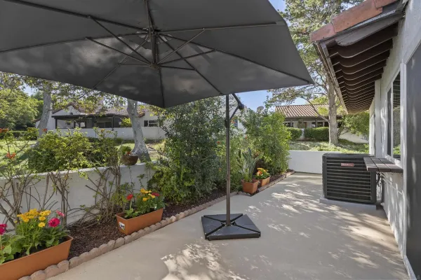 a backyard of a house with table and chairs under an umbrella