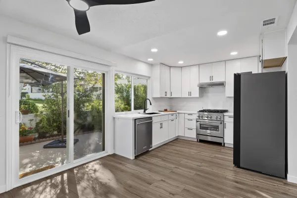 a kitchen with stainless steel appliances granite countertop a refrigerator a stove a sink and a granite counter tops with wooden floors