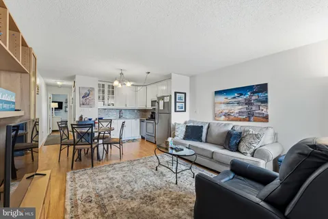 a kitchen with stainless steel appliances granite countertop a dining table chairs refrigerator and microwave