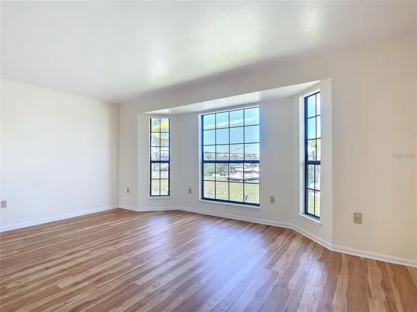 a view of an empty room with wooden floor and a ceiling fan