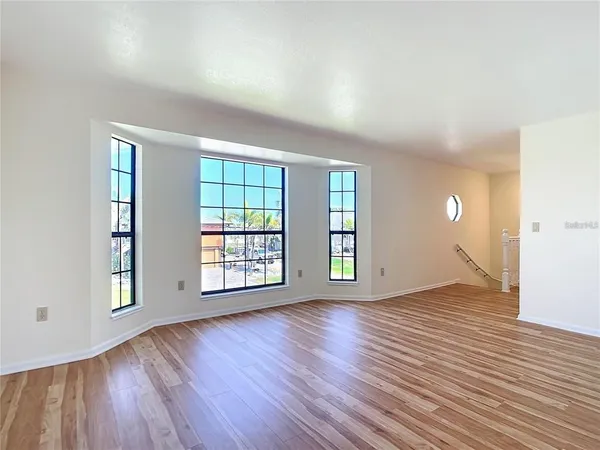 an empty room with wooden floor and windows