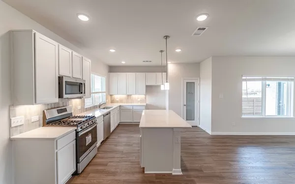 a large kitchen with stainless steel appliances lots of counter space and wooden floor