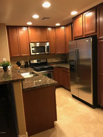 a kitchen with kitchen island granite countertop wooden cabinets a refrigerator and a sink