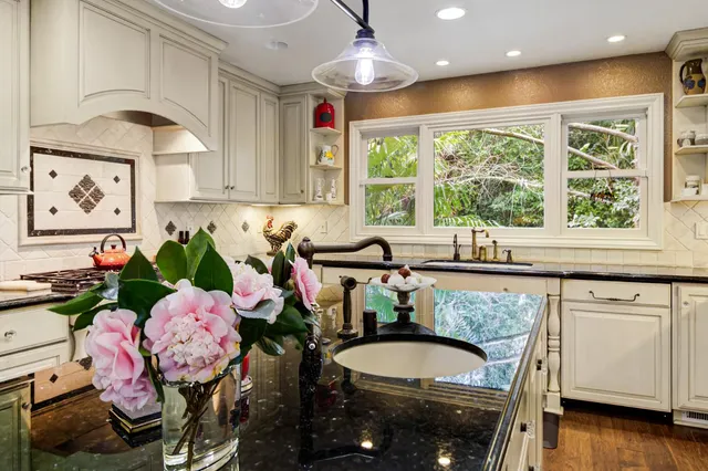 a kitchen with granite countertop a sink and white cabinets