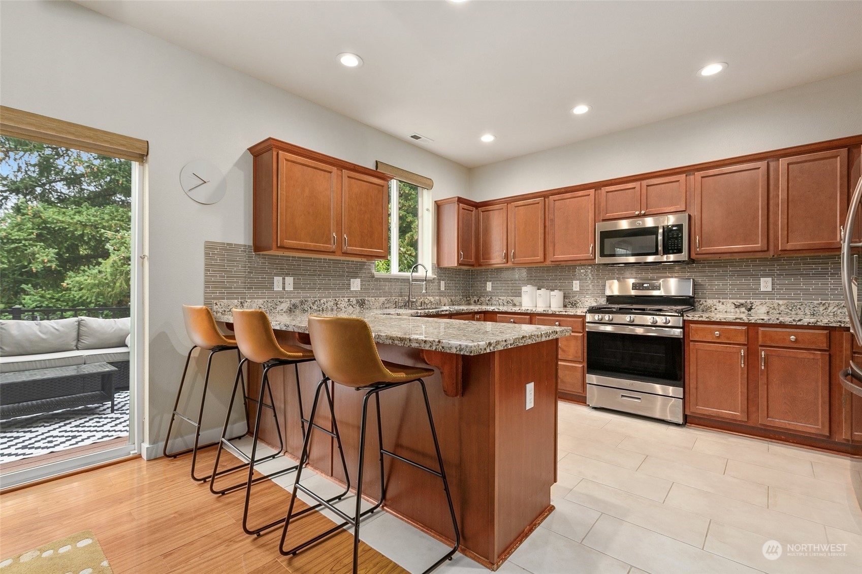 573 Field Place Northeast Renton, WA 98059 - Photo 10 of 34 a kitchen with granite countertop wooden cabinets a stove a microwave a island with a dining table and chairs