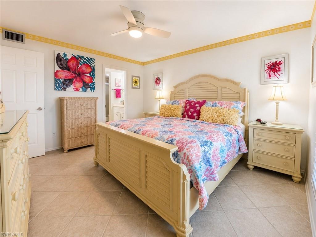 600 Neapolitan Way, Unit 449 Naples, FL 34103 - Photo 13 of 44 Bedroom featuring a light-colored furniture set with slatted details, neutral tile flooring, and a ceiling fan with integrated lighting