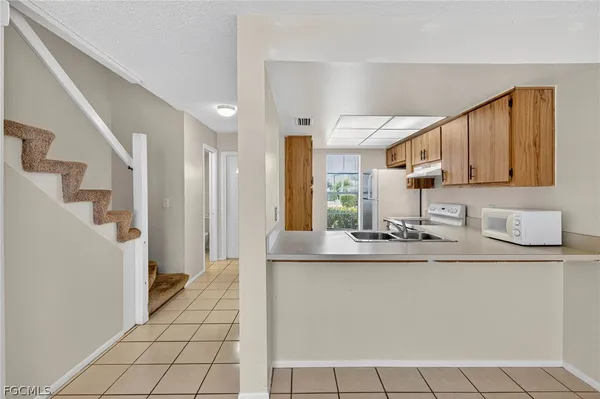 a kitchen with stainless steel appliances a sink a stove a refrigerator cabinets and a window