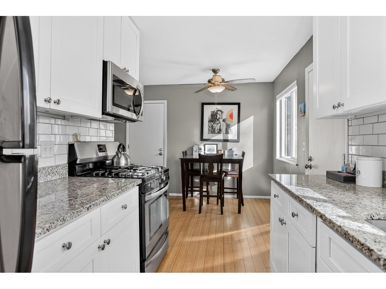 10696 Newcombe Street Westminster, CO 80021 - Photo 12 of 36 a kitchen with stainless steel appliances granite countertop a stove top oven a sink a dining table and chairs