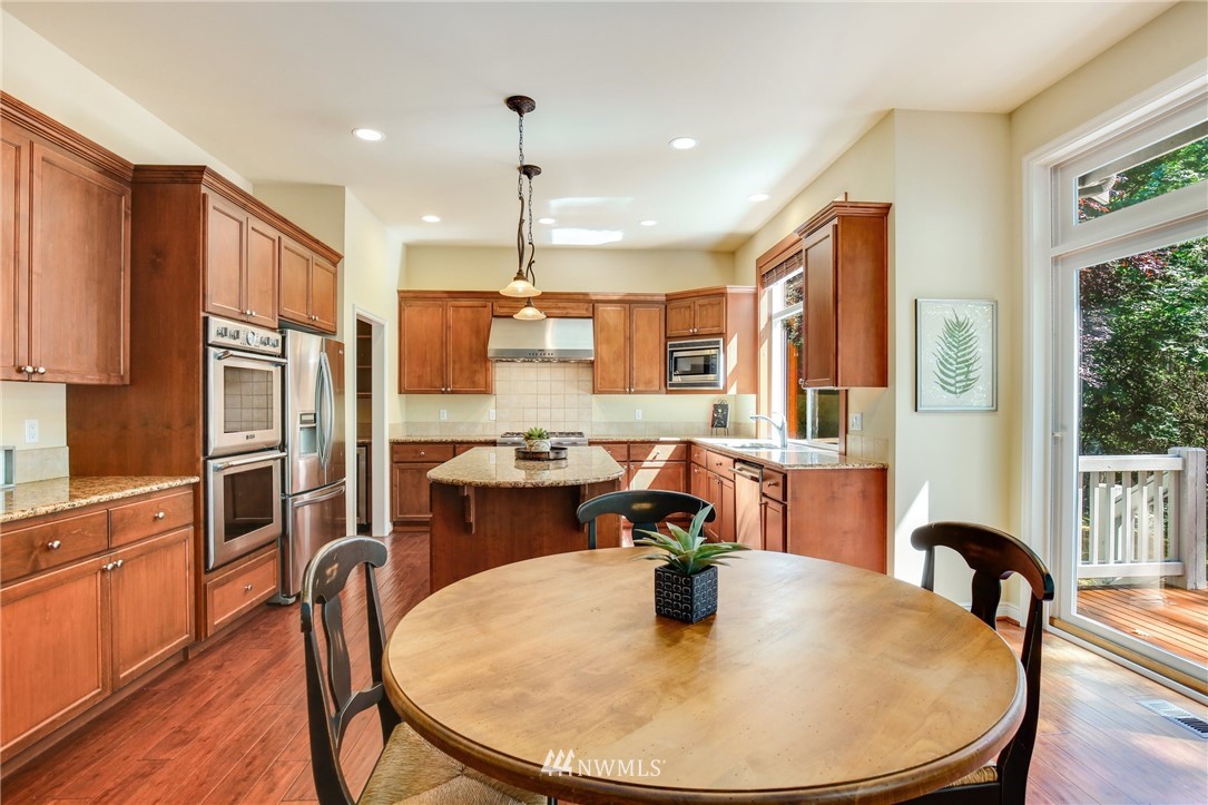 807 South 36th Place Renton, WA 98055 - Photo 15 of 39 a kitchen with stainless steel appliances granite countertop a stove a refrigerator a dining table and chairs with wooden floor