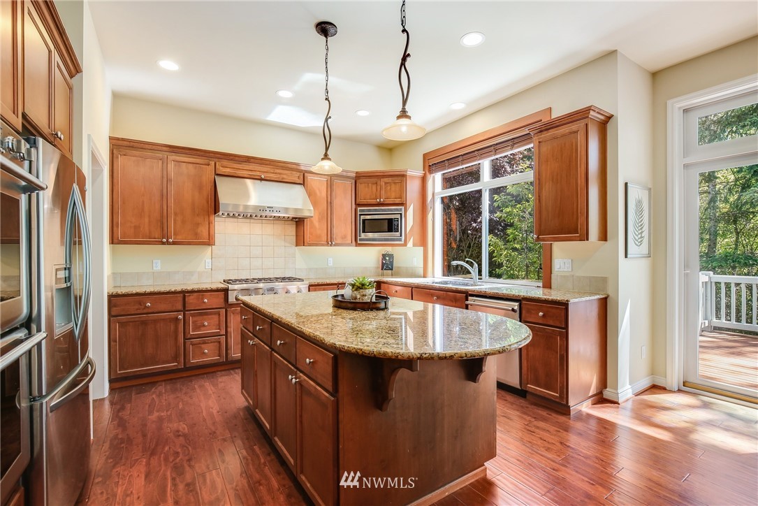 807 South 36th Place Renton, WA 98055 - Photo 10 of 39 a kitchen with stainless steel appliances granite countertop a sink a stove and a wooden floors