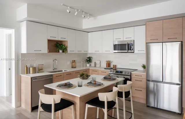 a kitchen with stainless steel appliances a white table and chairs in it