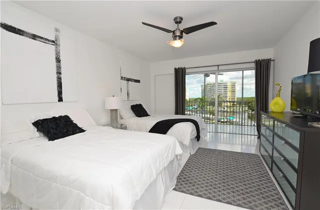 a bedroom with a bed a flat screen tv and a large window