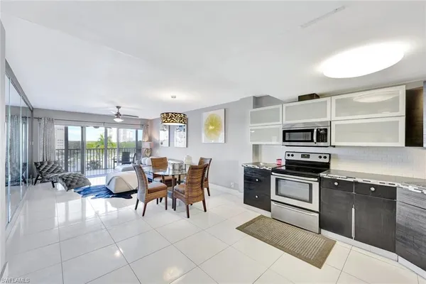 a kitchen with stainless steel appliances granite countertop a stove top oven a sink dishwasher a dining table and chairs with wooden floor