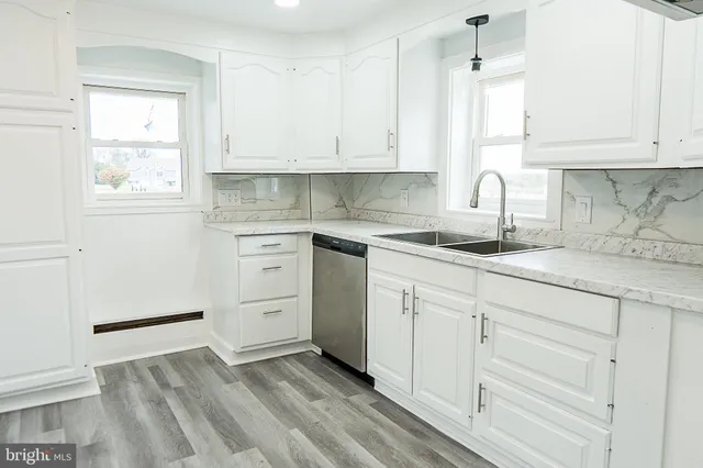 a kitchen with white cabinets appliances a sink and a window