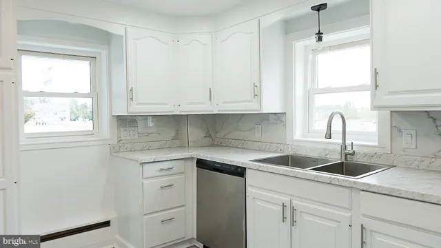 a kitchen with white cabinets and window