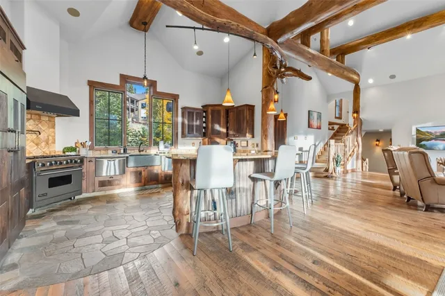 a kitchen with stainless steel appliances granite countertop a stove top oven a dining table and chairs with wooden floor