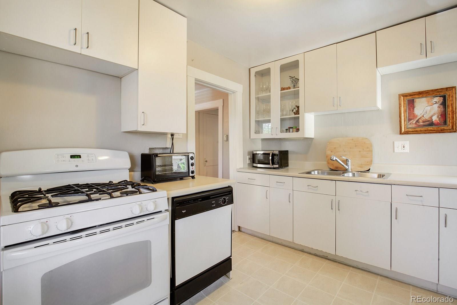 3877 Perry Street Denver, CO 80212 - Photo 11 of 23 a kitchen with granite countertop white cabinets and white appliances