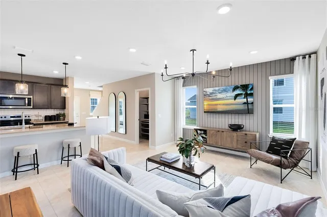 a living room with furniture kitchen view and a large window